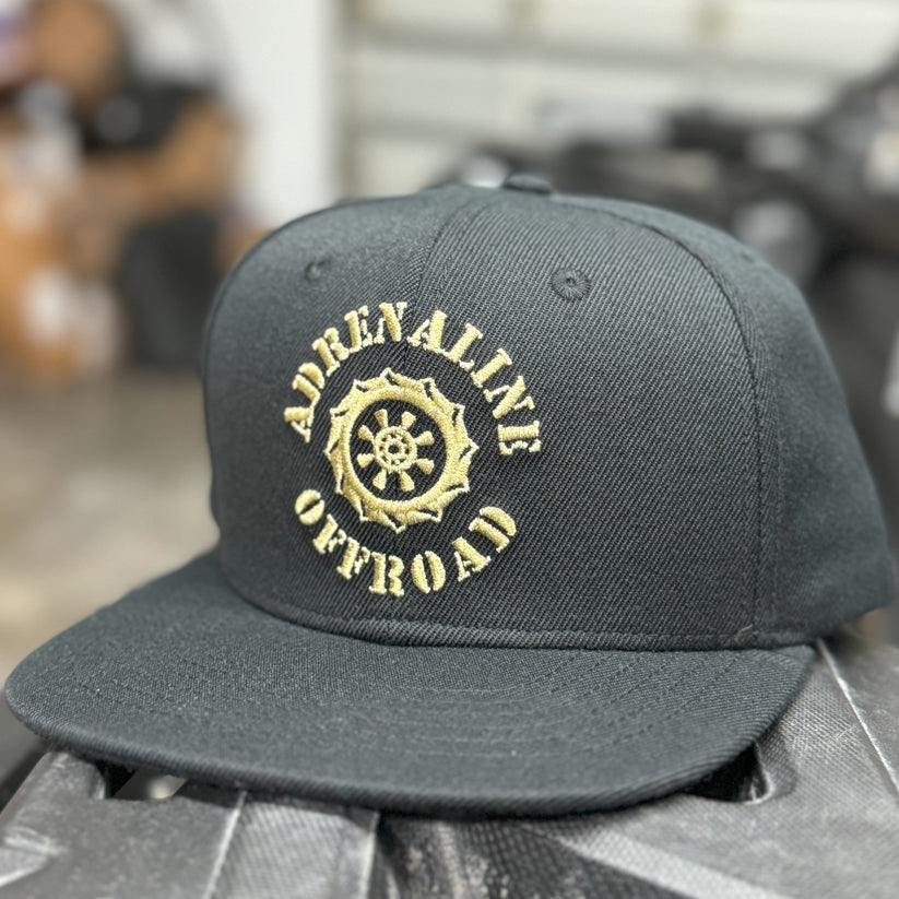 Gray cap with gold 'Adrenaline Offroad' logo on a blurred background