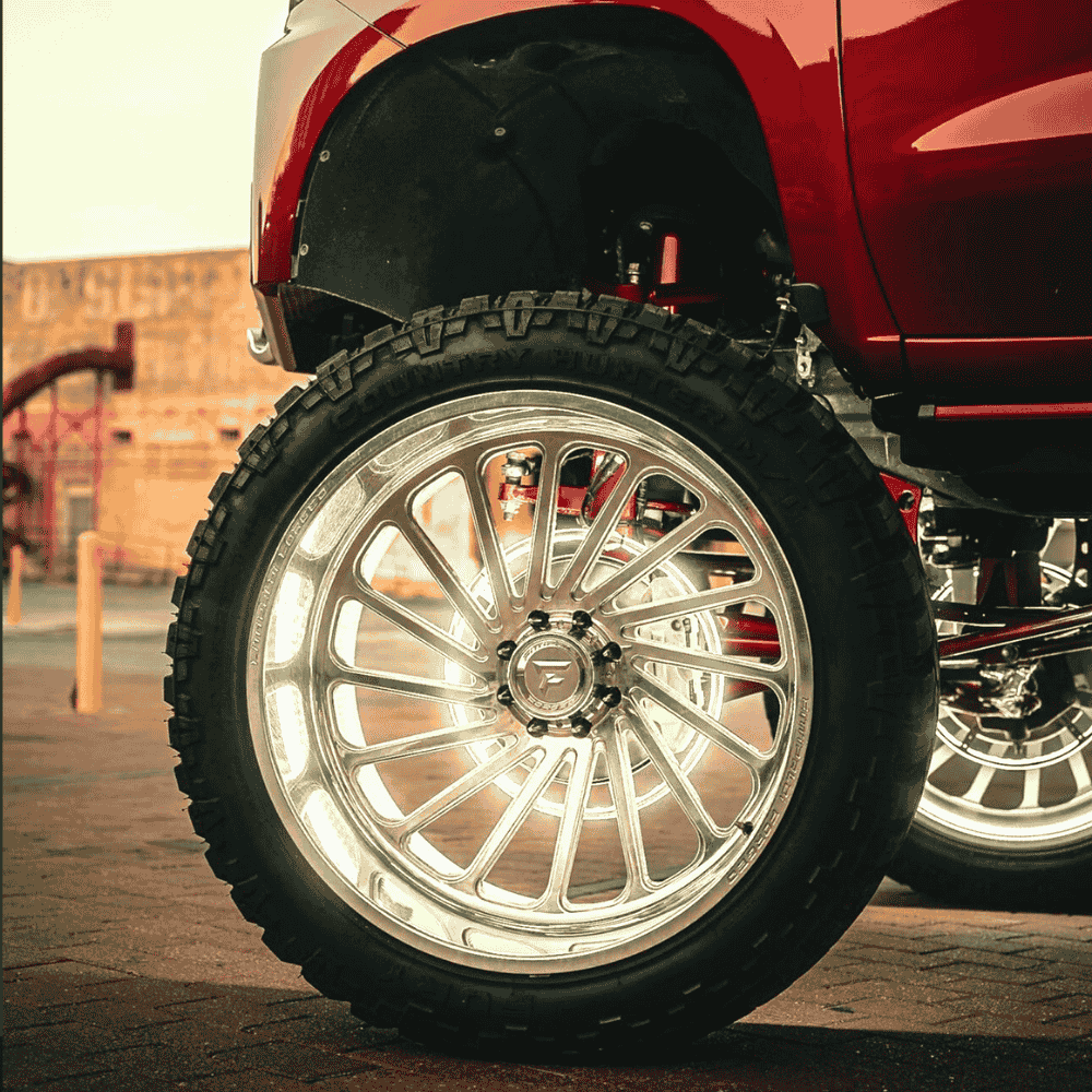 Close-up of a red vehicle's wheel with a shiny silver rim on a paved surface.